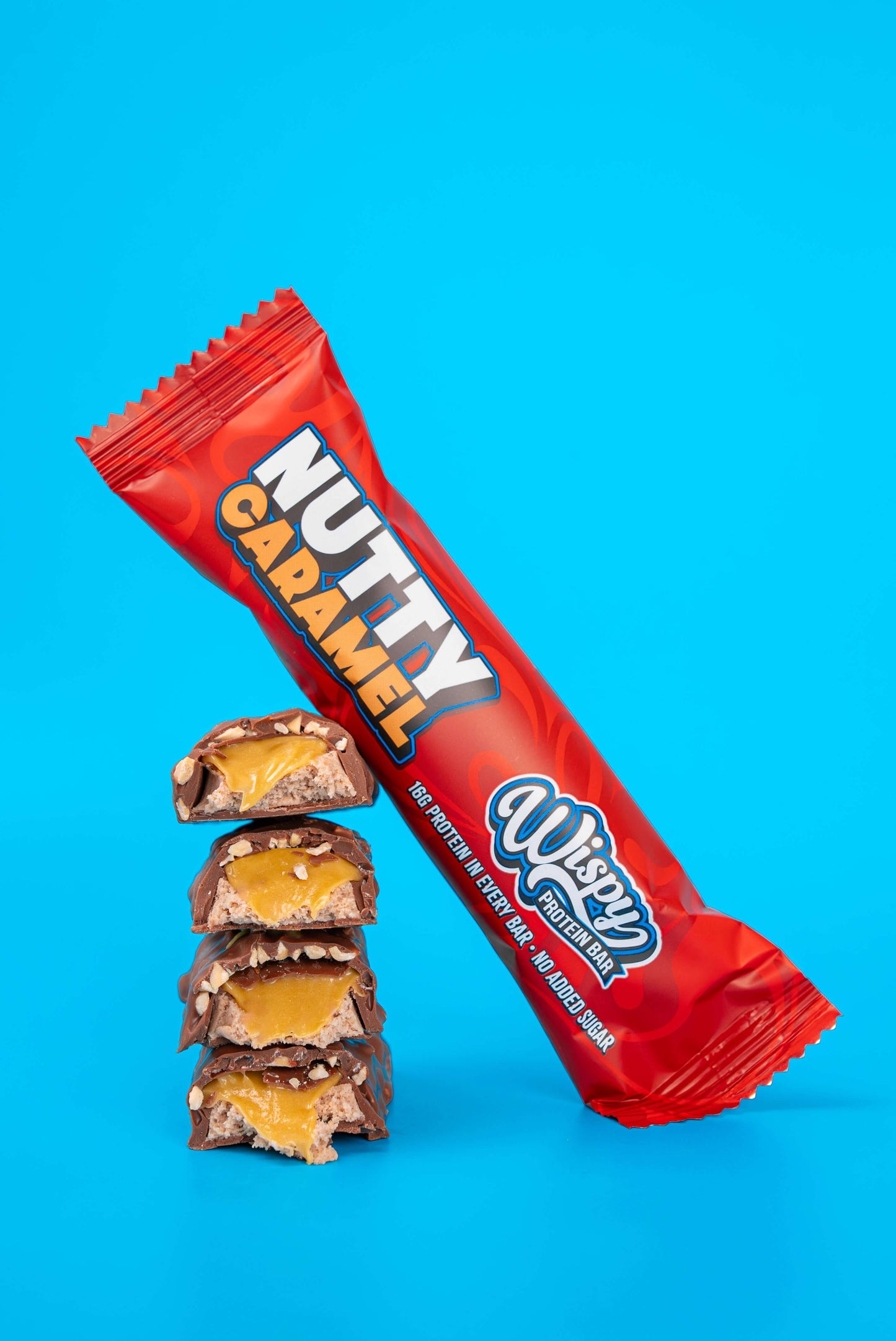 Wispy Eiwitreep verpakking in de smaak Nutty Caramel leunend tegen opengesneden repen waarvan je de binnenkant ziet