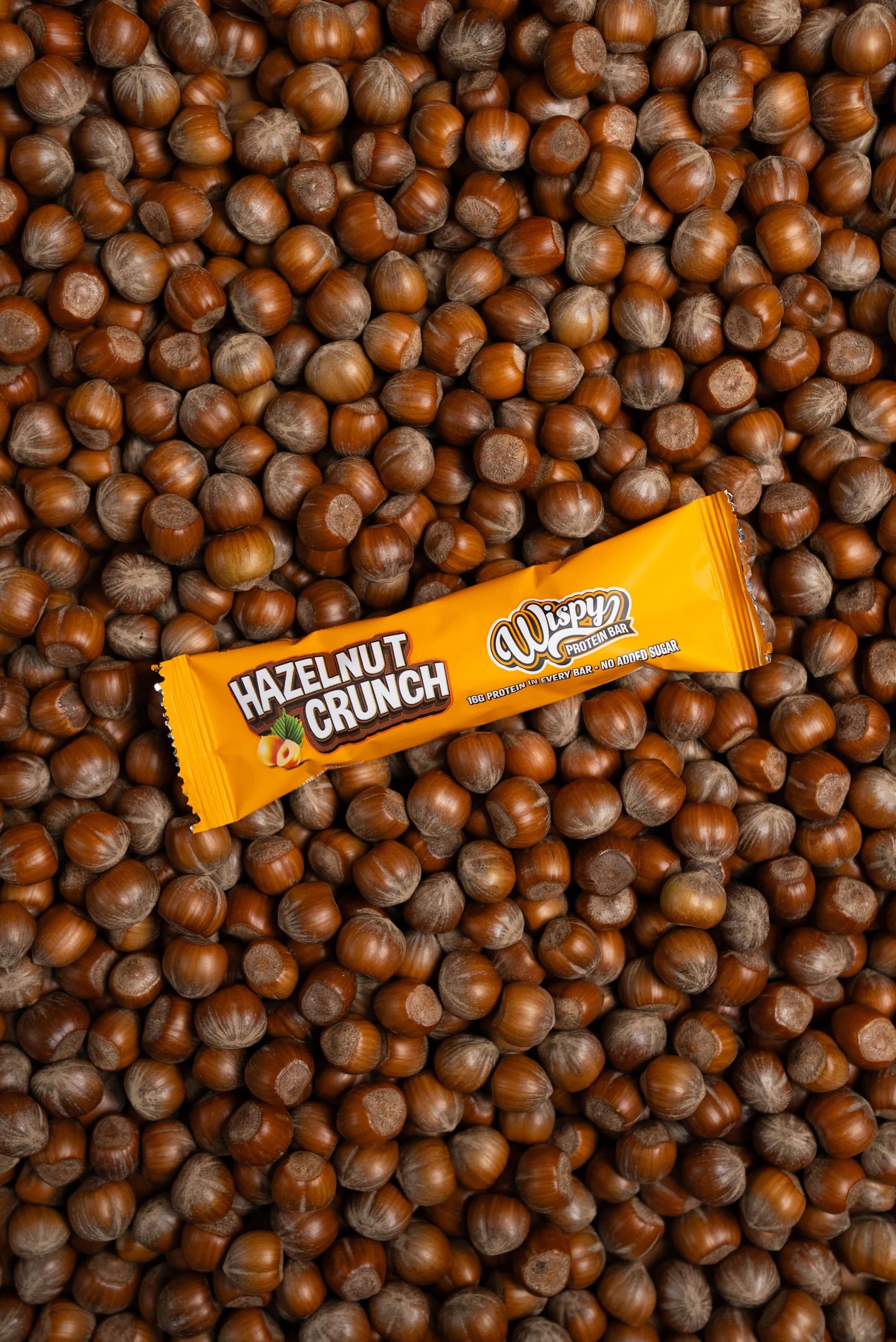 Wispy eiwitreep verpakking in de smaak hazelnut crunch met een achtergrond met alleen maar hazelnoten